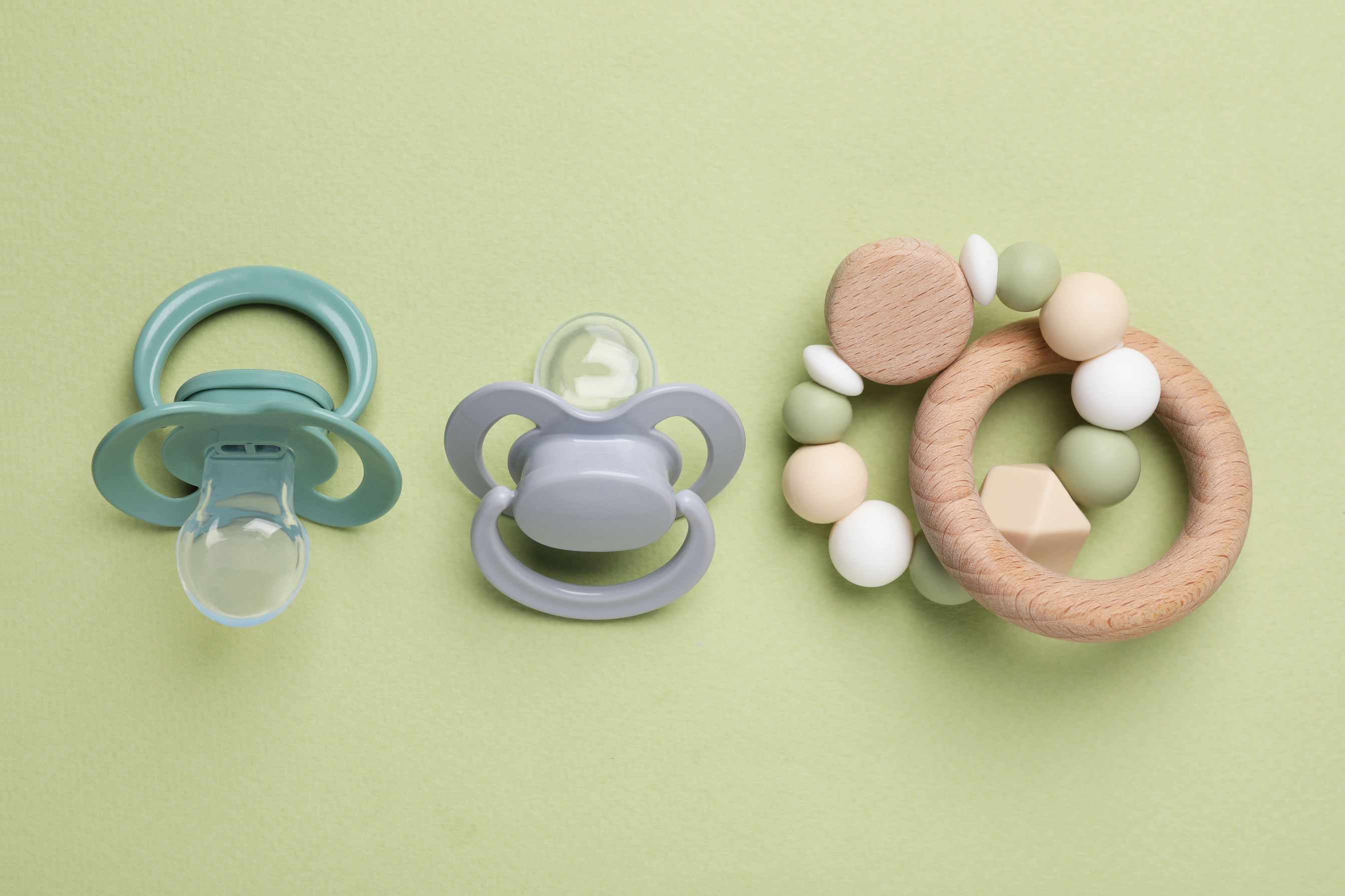 Flat Lay Composition with Pacifiers and Other Baby Stuff on Pale